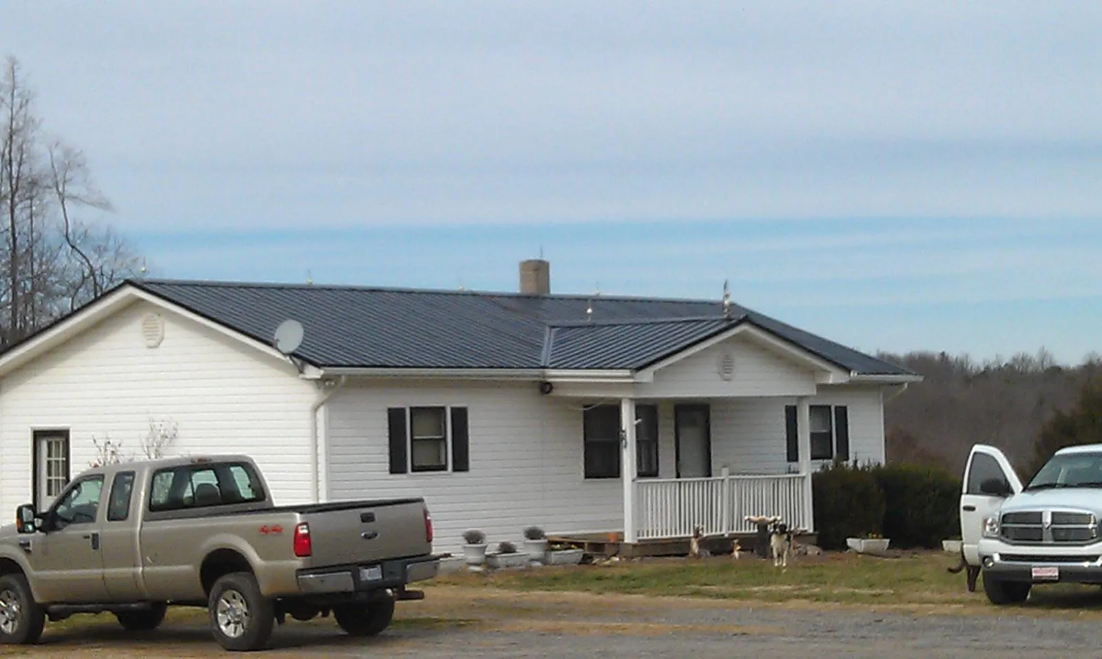 Finished dark metal roof on a white ranch home with work trucks parked in Everett