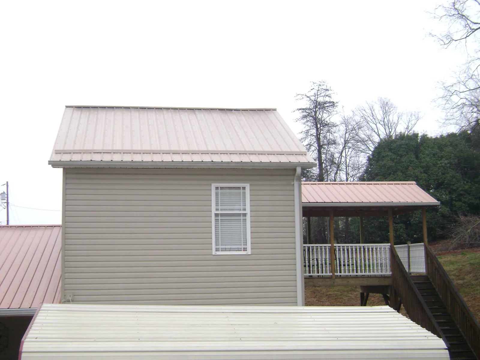 Tan metal roofs on a two story addition and attached porch, from a Roof Replacement job in Everett